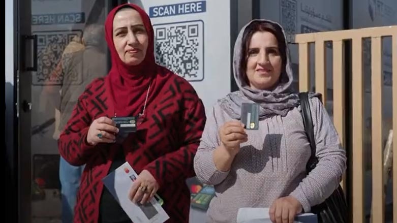 Two public employees showing their credit cards at one of the newly installed ATMs in Erbil. (Photo: KRG)