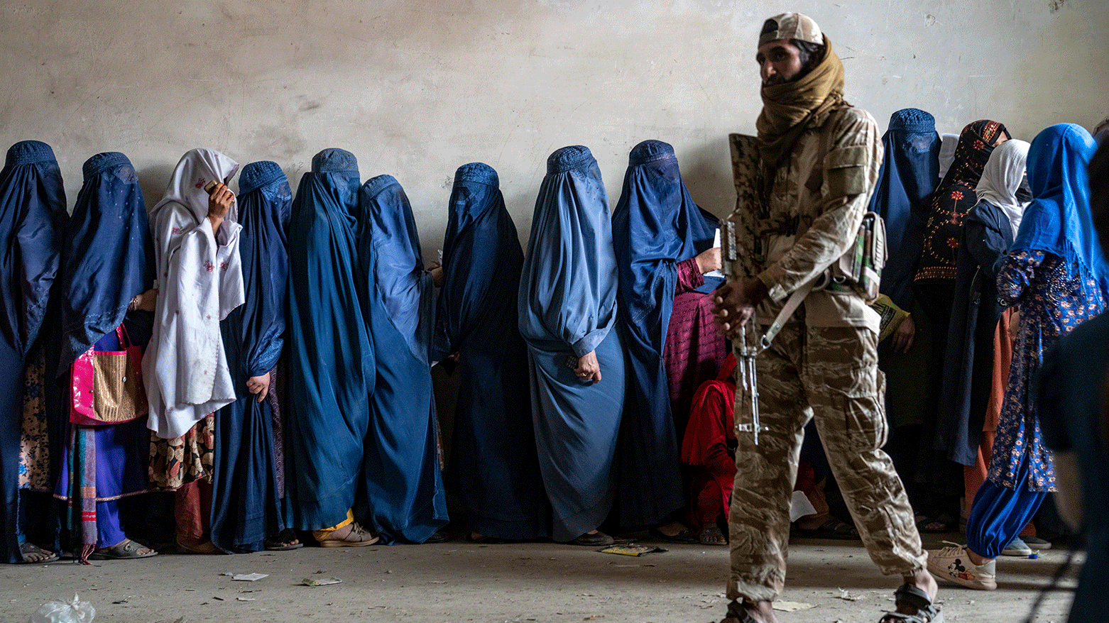 A Taliban fighter stands guard as women wait to receive food rations distributed by a humanitarian aid group, in Kabul, Afghanistan, on May 23, 2023. (Photo: AP)