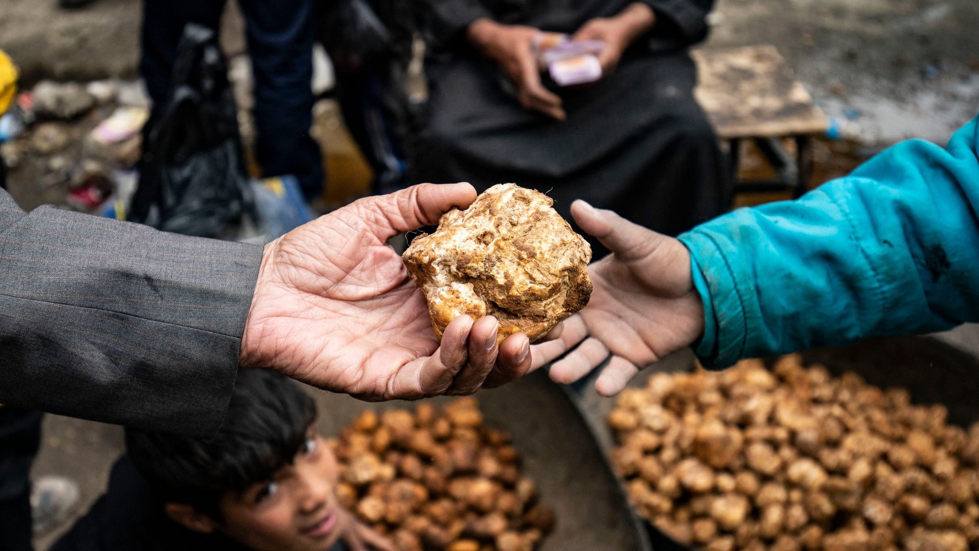 A customer buys a desert truffle from a merchant in a market in Syria's rebel-held northern city of Raqa on March 14, 2023. (Photo: Delil souleiman/AFP)