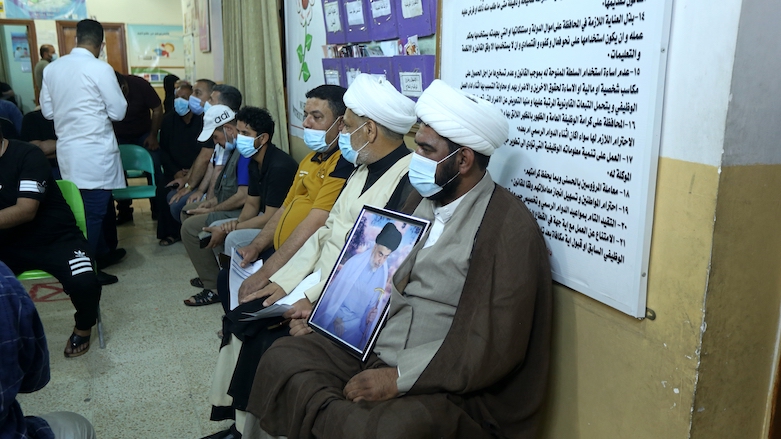 A follower of Shia cleric Muqtada al-Sadr holds a picture of him while waiting with others to receive a dose of the Chinese Sinopharm coronavirus vaccine in Sadr City, Baghdad, Iraq, May 4, 2021. (Photo: Hadi Mizban/AP)