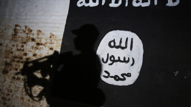 The shadow of a member of Iraq's security forces is cast on the flag of ISIS in 2017 at a town once controlled by the extremist organization. (Photo: AFP/Ahmad al-Rubaye)