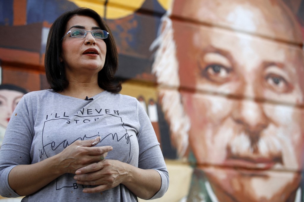 Iraqi artist Wijdan al-Majed speaks during an interview in front of her mural depicting Iraqi poet Muzzafar al-Nawab on a concrete structure in the capital Baghdad, April 26, 2022. (Photo: Ahmad Al-Rubaye/AFP)