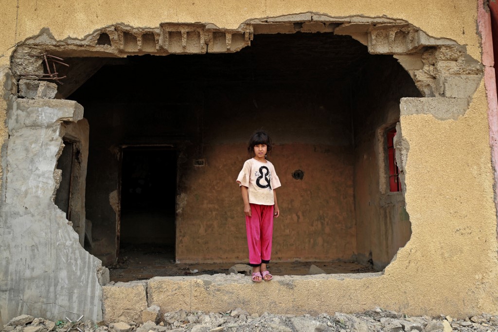 A girl looks out her damaged house in the war-ravaged village of Habash, on April 25, 2022. (Photo: Ahmad Al-Rubaye/AFP)