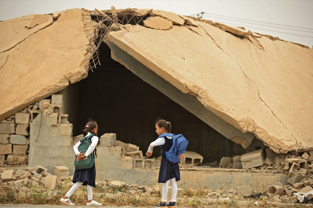 Iraqi pupils walk past a destroyed house in the war-ravaged village of Habash, on April 25, 2022. (Photo: Ahmad Al-Rubaye/AFP)