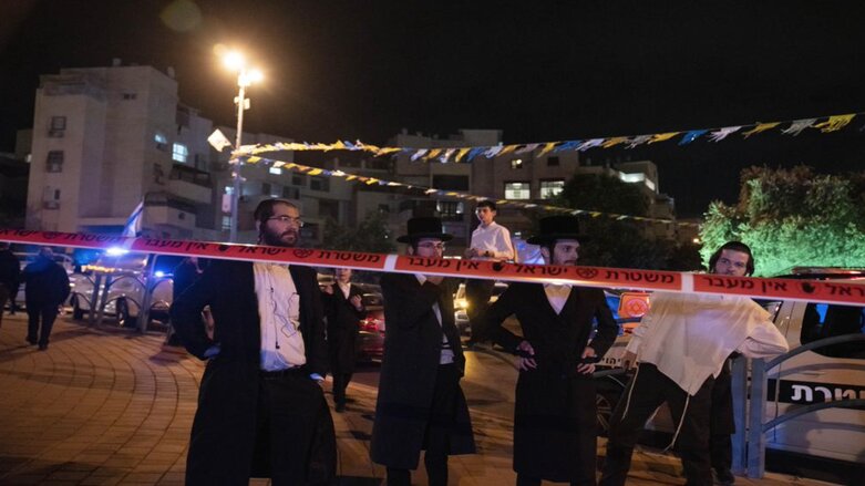 Ultra-Orthodox Jews stand behind police tape after a stabbing attack in the town of Elad, Israel, Thursday, May 5, 2022. (Photo: Maya Alleruzzo/AP)