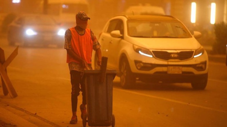 An Iraqi worker cleans the street during a severe dust storm in the Iraqi capital Baghdad on May 1, 2022. (Photo: AFP)