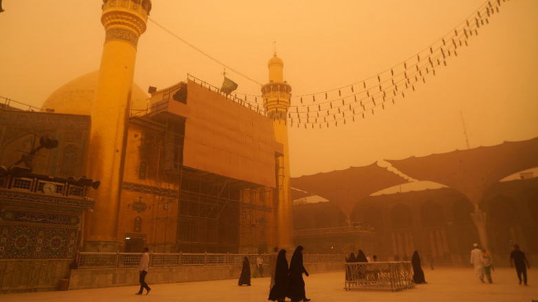 Visitors walk by at the Imam Ali shrine during a sandstorm in Iraq's holy city of Najaf, May 16, 2022. (Photo: Qassem Al-Kaabi/AFP)