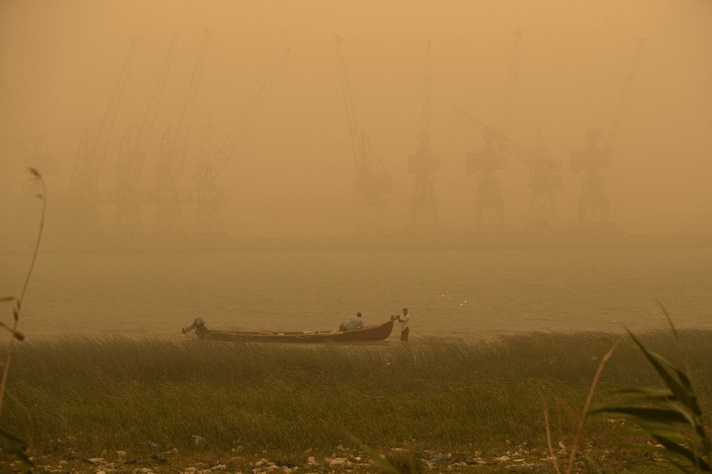 Fishermen sit in a boat opposite the port of Basra, also known as al-Maqal port, in Iraq's southern city of Basra in the Shatt al-Arab river on during a sandstorm sweeping the country, May 23, 2022. (Photo: Hussein Faleh/AFP)