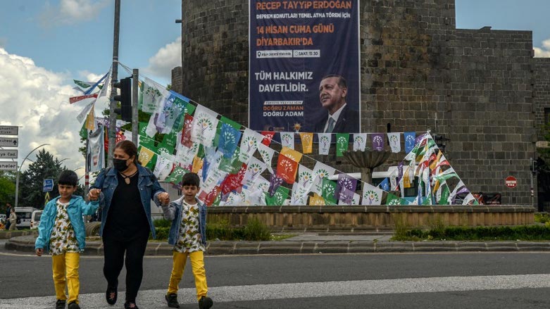 A woman stands in front of election campaign flags hanging on historical Sur castle at the historical Sur district in Diyarbakir, southeastern Turkey (Photo: ILYAS AKENGIN / AFP)