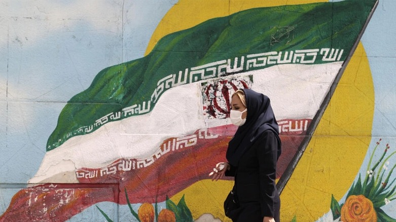 امرأة إيرانية تمشي قرب جدار مرسوم عليه علم إيراني في طهران في 10 نيسان/أبريل 2023 © عطا كناره / ا ف ب