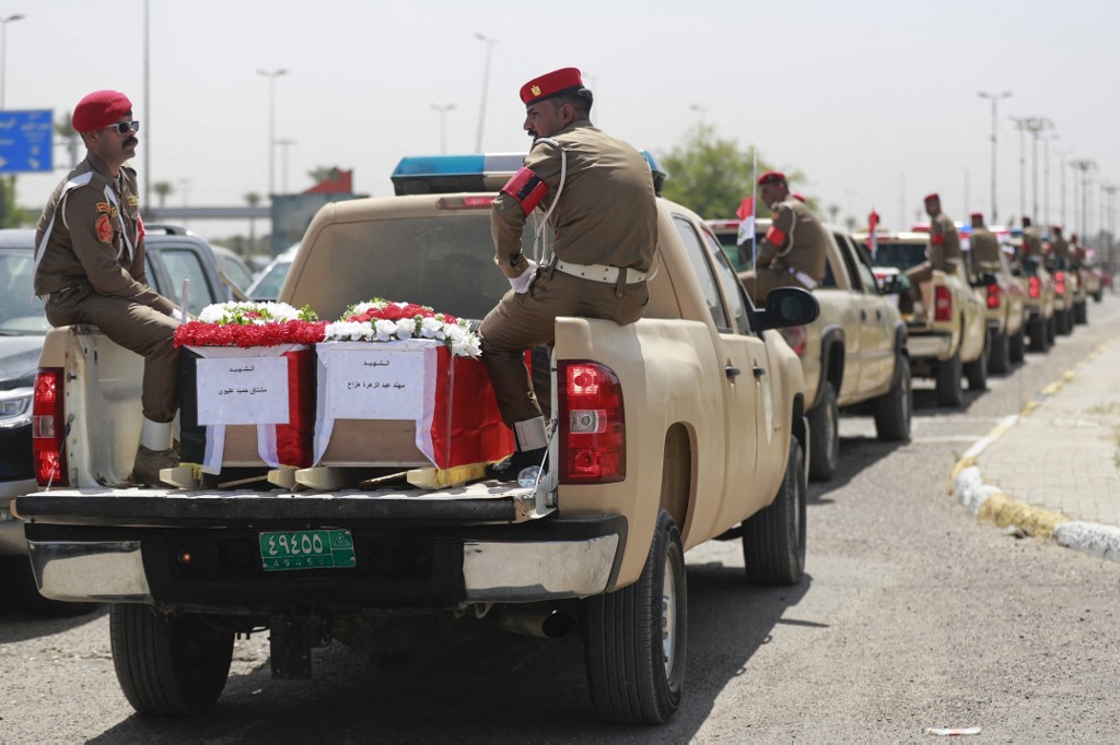 Iraqi military vehicles transport coffins containing DNA-identified remains of inmates at the Badush prison, killed by Islamic State (IS) group jihadists in 2014 and found in mass graves in 2017, May 16, 2023. (Photo: Ahmad Al-Rubaye/AFP)