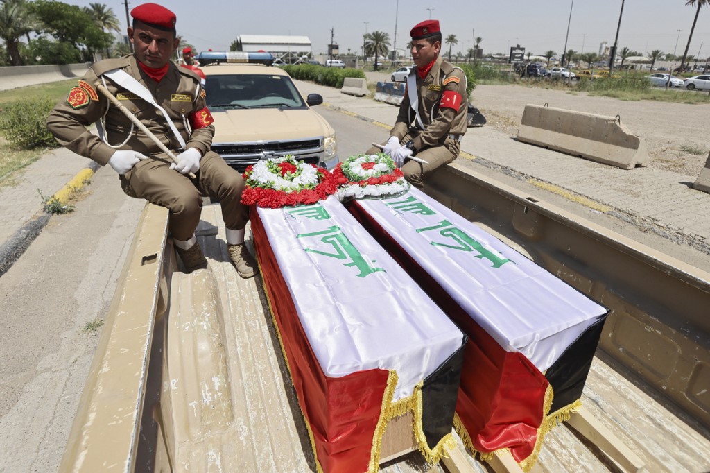 Iraqi military vehicles transport coffins containing DNA-identified remains of inmates at the Badush prison, killed by Islamic State (IS) group jihadists in 2014 and found in mass graves in 2017, May 16, 2023. (Photo: Ahmad Al-Rubaye/AFP)