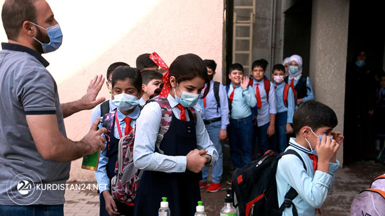 A teacher sanitizes students' hands on the playground, at a school in Baghdad, Iraq, Nov. 1, 2021.(AP Photo/Hadi Mizban)