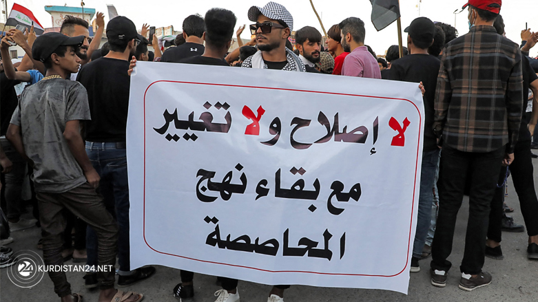 A demonstrator holds up a banner reading "no reform and no change while maintaining the allotment scheme", during a protest in al-Haboubi Square in the centre of Iraq's city of Nasiriyah, Oct. 25, 2021. (Photo: Asaad Niazi/AFP)