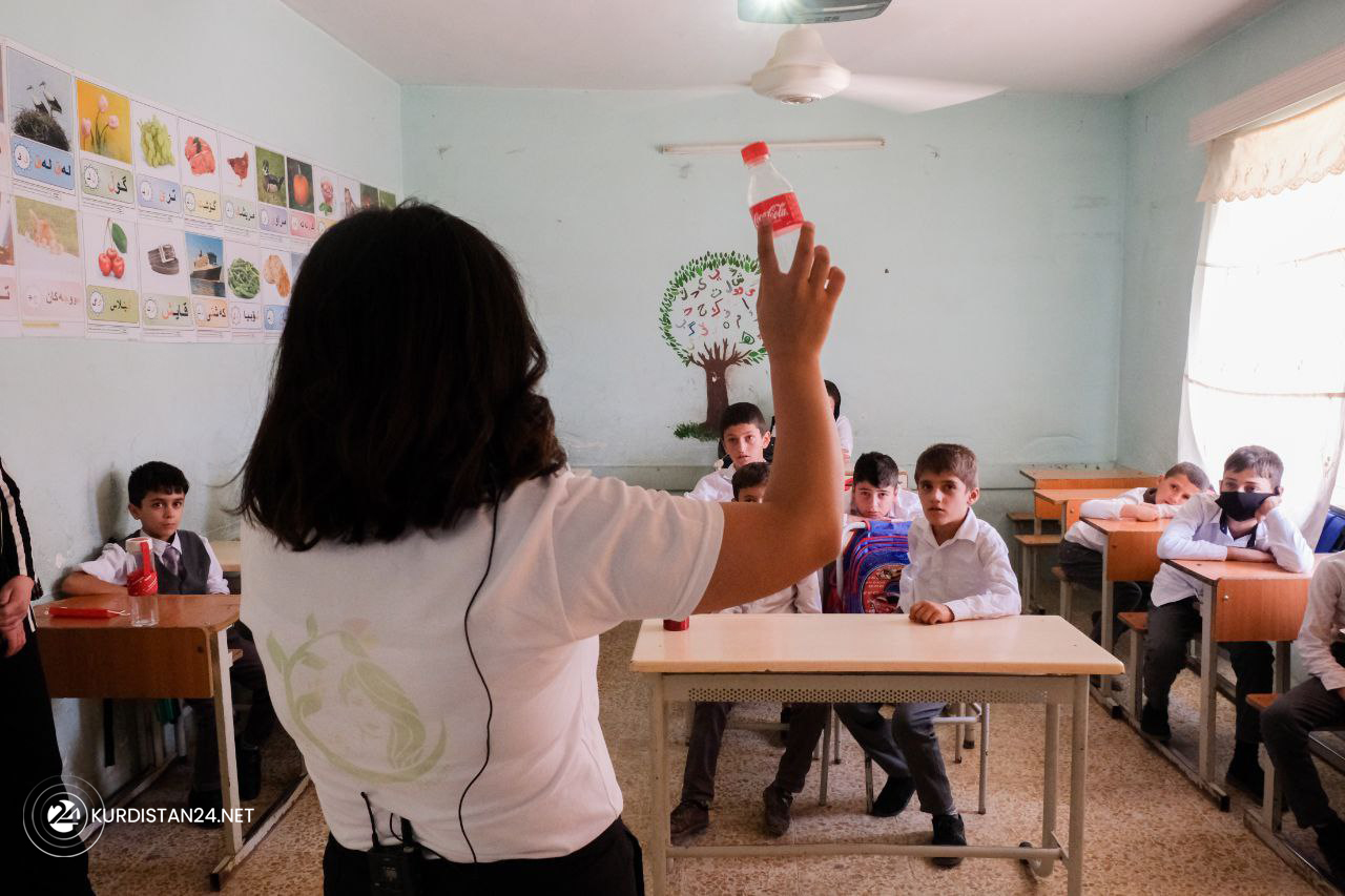 One of the environmentalists holds a plastic bottle of a soft drink, explaining the waste's adverse effects on the environment. (Photo: Kurdish Enlightened Women)