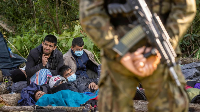 A Polish border guard stands watch over a group of migrants (photo AFP)