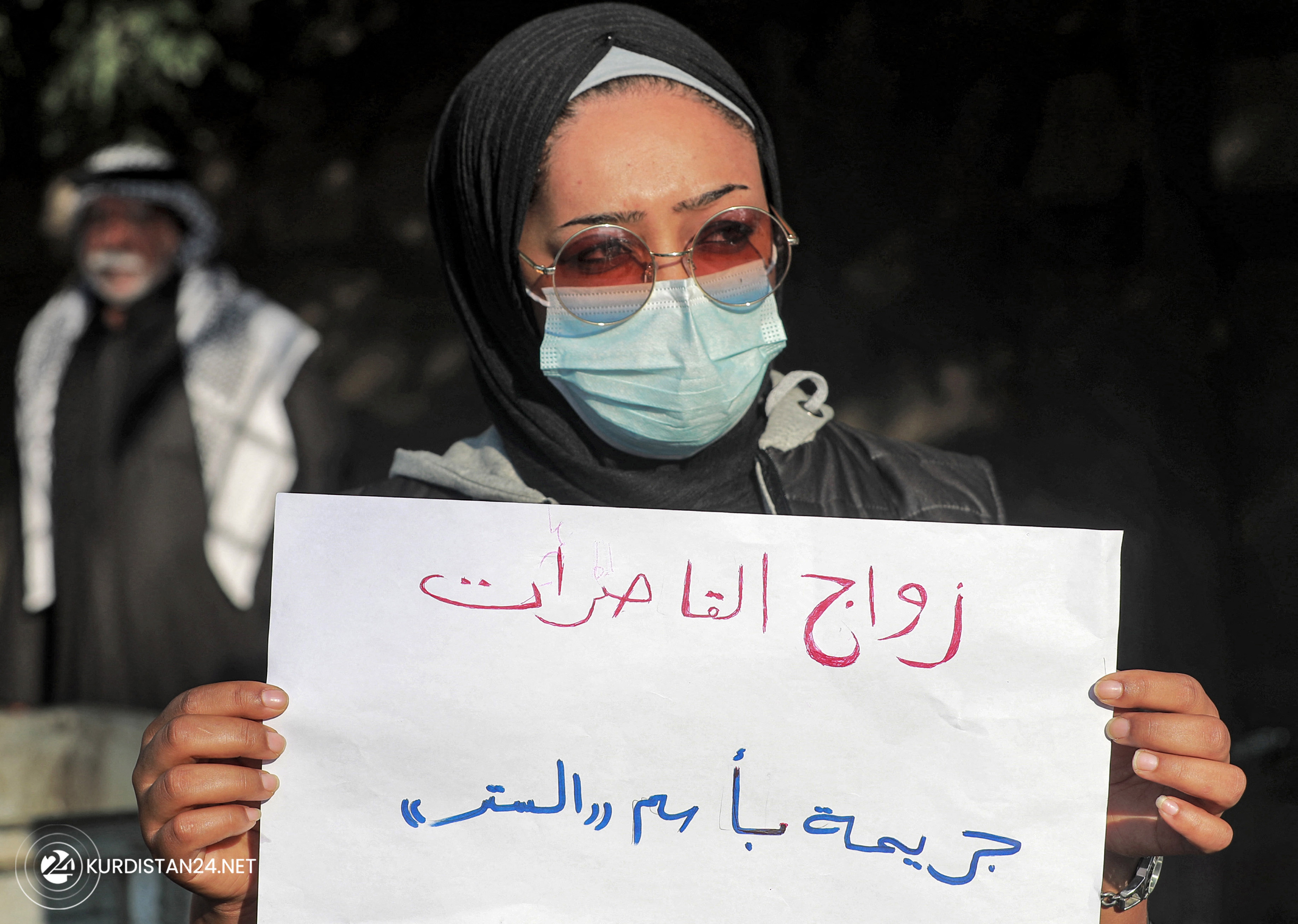A woman holds up a sign reading in Arabic 