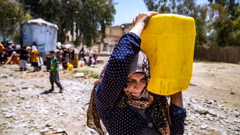 A Syrian woman carries a container of water provided by the UNICEF in Syria's northeastern city of Hasakah, on July 8 2021, after disruption in water supply from the Allouk station. (AFP photo)