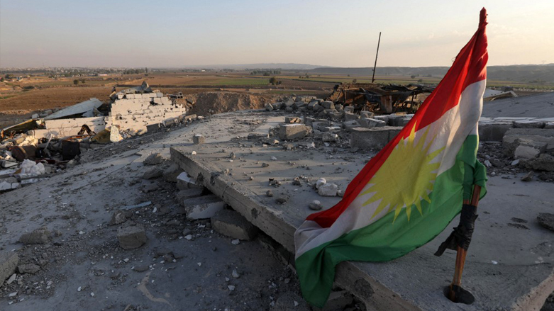 A Kurdish flag is pictured amid the destruction caused by a reported Iranian rocket attack near town city of Altun Kupri (Perdi), north of Kirkuk, in Iraq's autonomous Kurdistan region, Nov. 23, 2022. (Photo: Safin Hamed/AFP)