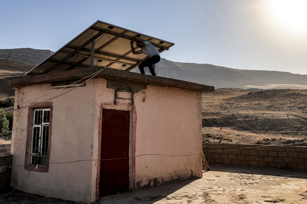 A man inspects solar panels installed atop the roof of a house in the Hazer Merd village near Kurdistan Region's Sulaimani, Sept. 19, 2023. (Photo: Ahmed Al-Rubaye/AFP)