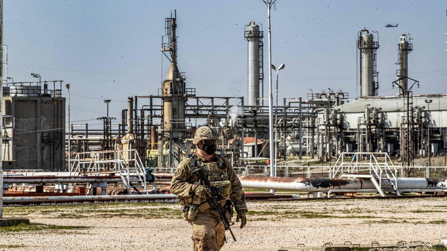 A United States soldier looks on while an AH-64 Apache assault helicopter flies above during a patrol by the Suwaydiyah oil fields in Hassakeh province, northeastern Syria, Feb. 13, 2021. (Photo: AFP)