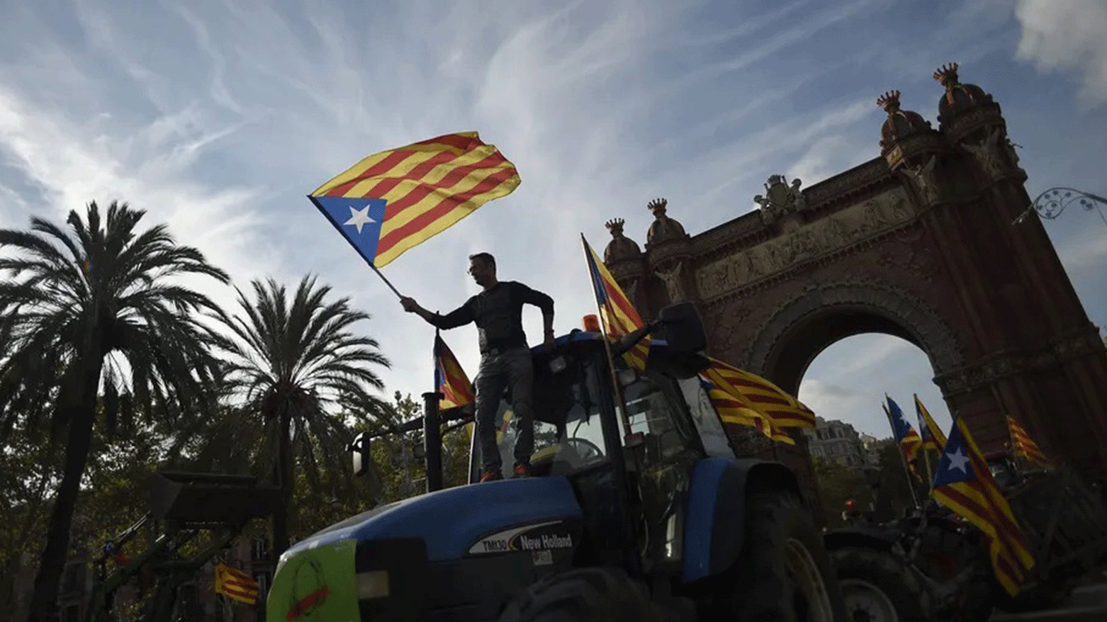 Supporters of Catalan independence wave Catalan flags as they drive with tractors through the Arc de Triomf (Triumphal Arch) in Barcelona on October 10, 2017. (Photo: AFP)