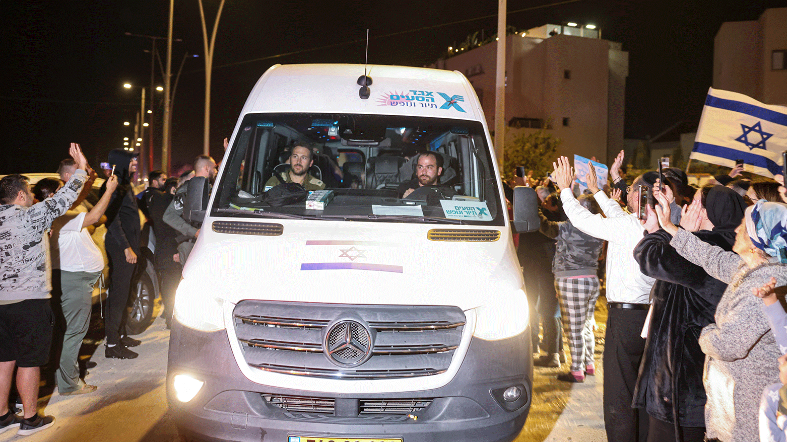 People cheer as a vehicle carrying hostages released by Hamas drives towards an army base in Ofakim, southern Israel, on November 26, 2023. (Photo: AFP)