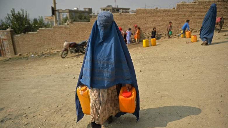 A burqa-clad woman carries containers filled with drinking water after fetching from a tanker in Kabul on October 1, 2021. (Photo: Hoshang Hashimi / AFP)