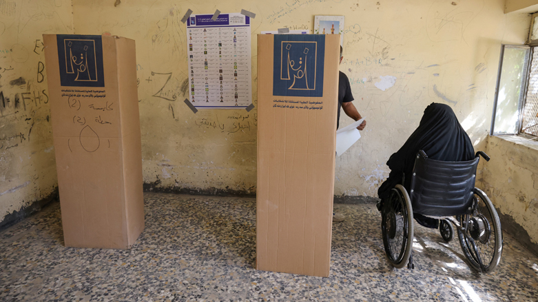A disabled Iraqi elderly woman is helped to cast her vote during voting in early parliamentary elections at a polling station in Iraq's capital Baghdad, Oct. 10, 2021. (Photo: Ahmad al-Rubaye/AFP)