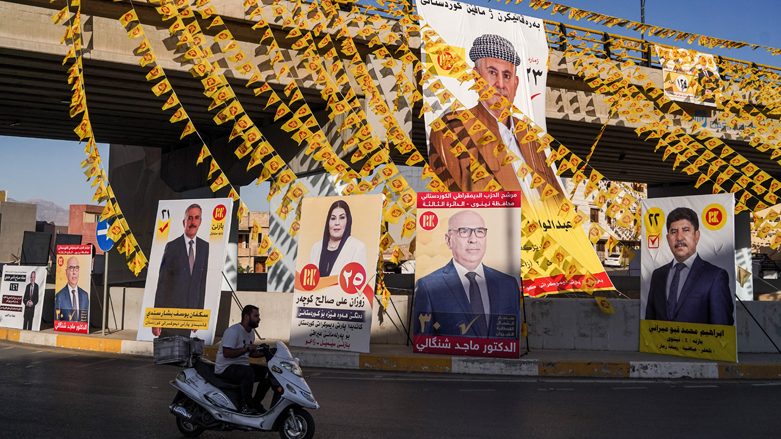 A man rides a scooter along a roundabout past electoral banners for KDP candidates running in Iraq's October 2021 elections in Kurdistan Region's Zakho province, Oct. 5, 2021. (Photo: Ismael Adnan/AFP)