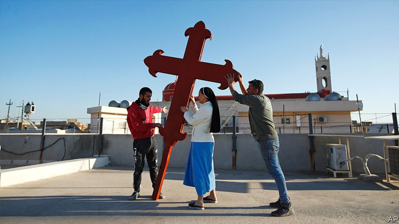 Iraqi Christians place a cross on a church in Qaraqosh district, Iraq. Feb. 22, 2021. (Photo: AP)