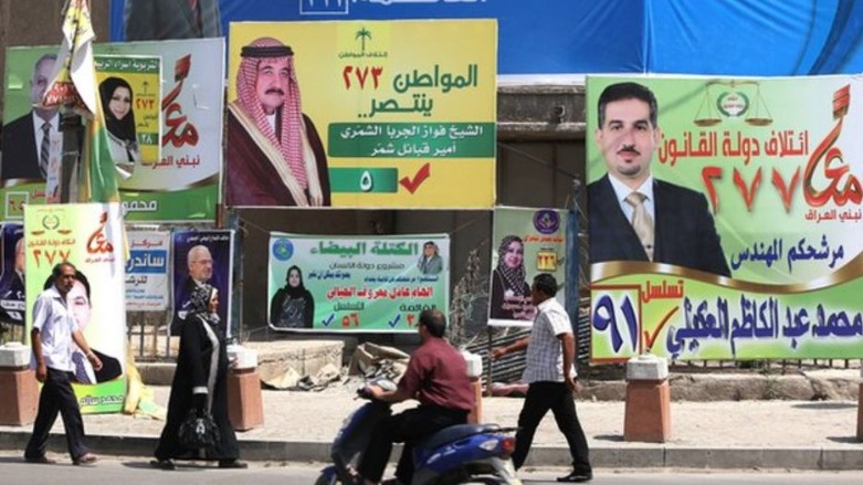 Iraqi pedestrians walk past campaign posters for the 2021 parliamentary election in Baghdad. (Photo: AFP)