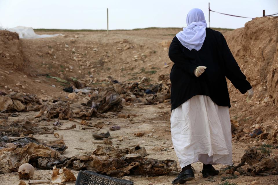 A Yezidi woman walks in the remains of people killed by Daesh at a mass grave near the Sinuni village, Sinjar district, Feb. 3, 2015. (Photo: Safin Hamid/AFP)