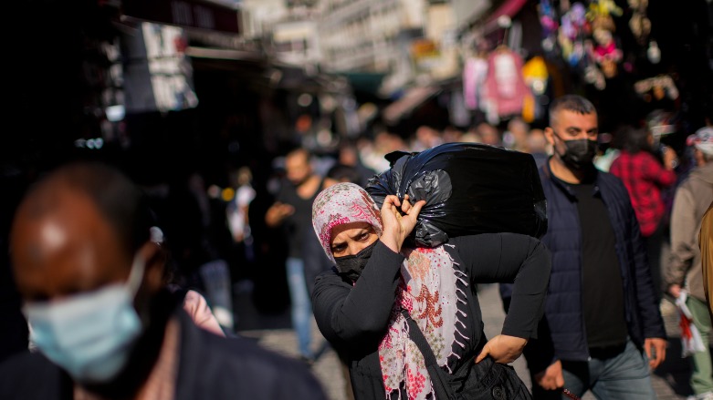 A woman carries a bag with goods on her shoulder in a street market at the Eminonu district in Istanbul, Turkey, Thursday, Oct. 21, 2021. (AP Photo/Francisco Seco)