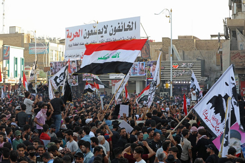Iraqi protesters lift placards and national flags during a rally to mark three years since nationwide demonstrations erupted against endemic corruption, at al-Habboubi square in the southern city of Nasiriyah, Oct. 1, 2022. (Photo: Asaad NIAZI/AFP)
