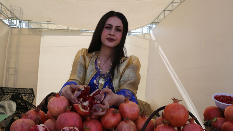 A Kurdish woman displays a cracked pomegranate at Halabja's autumn festival, Oct. 14, 2021. (Photo: Dana Hama Gharib/Kurdistan24)
