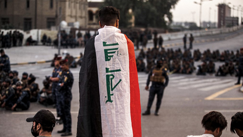 A demonstrator draped in the Iraqi national flag stands before security forces near al-Jumhuriya (Republic) bridge leading to the capital Baghdad's high-security Green Zone on Oct. 25, 2022. (Photo: Ahmad Al-Rubaye/AFP)