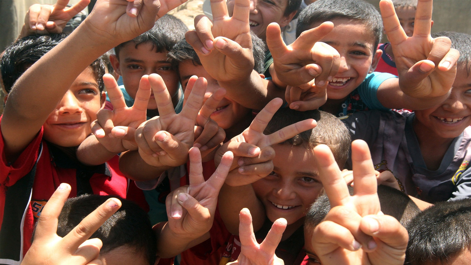 صورة تعبيرية لمجموعة أطفال يلوّحون بإشارة التفوّق (النصر)