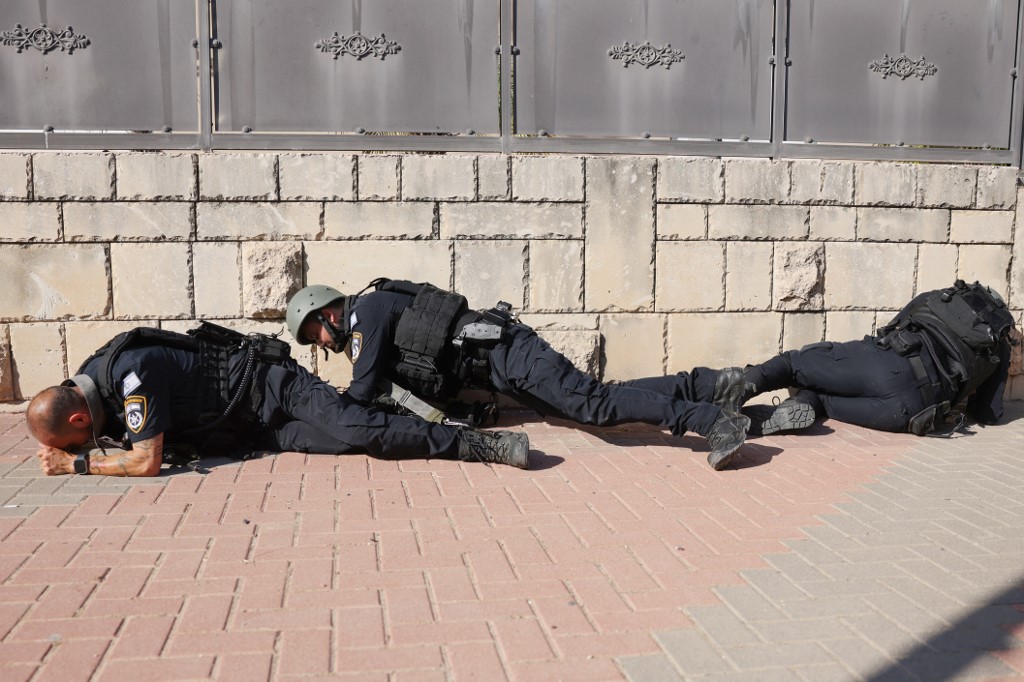 Members of the Israeli frorces take cover on the side of a street in Ashkelon as sirens wail while barrages of rockets are fired from the Gaza Strip into Israel, October 7, 2023. (Photo: Ahmad Gharabli/AFP)