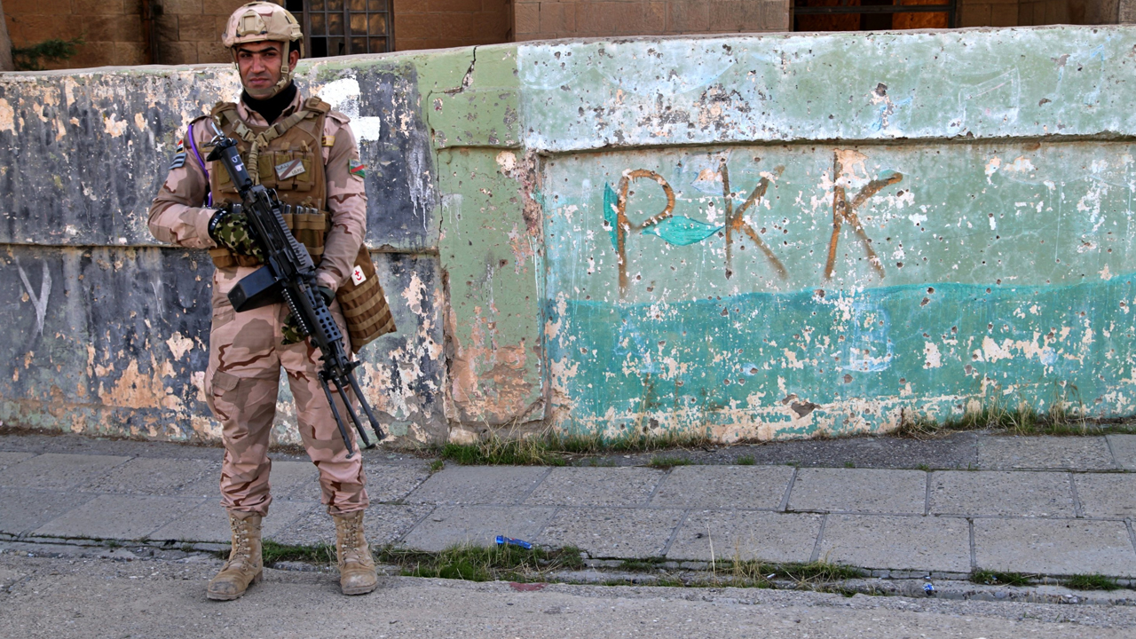 An Iraqi soldier stands against the backdrop of a wall on which the Kurdistan Workers' Party acronym has been inscribed, Dec. 4, 2020. (Photo: AP)
