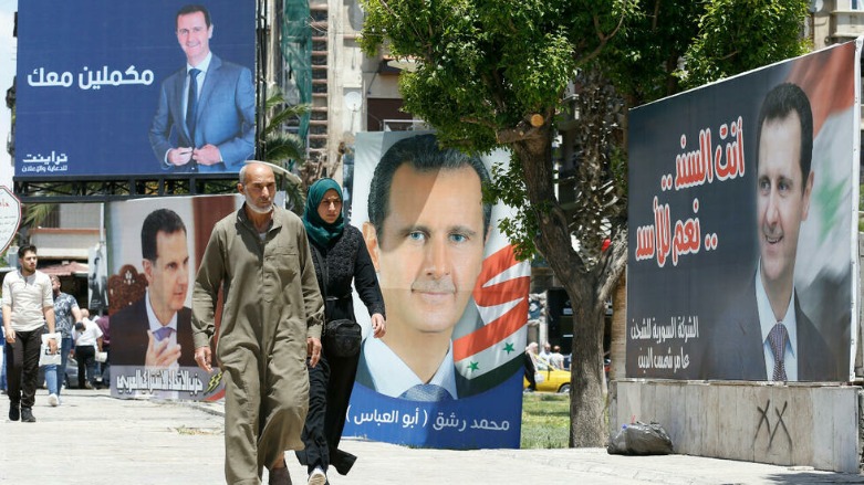 مارة أمام لافتات الحملة الانتخابية للرئيس السوري بشار الأسد في العاصمة دمشق- الصورة لفرانس 24