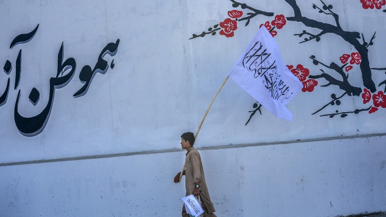 A boy walks along a street selling Taliban flags in Kabul on September 16, 2021. (Bulent Kilic / AFP)