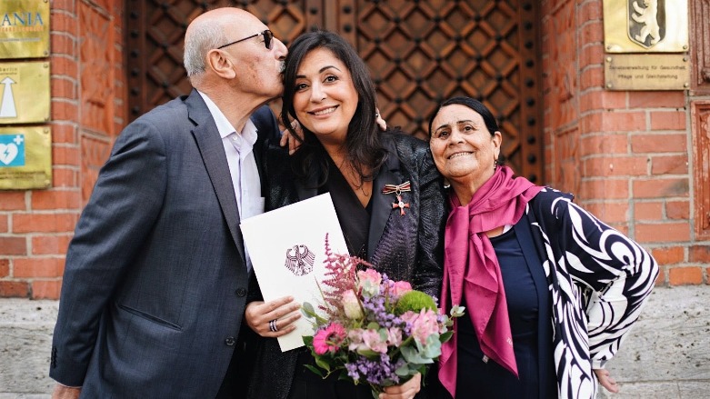 Düzen Tekkal (center) posed with her parents after receiving the German Order of Merit award for her contributions to German society in 2021 (Photo: Archive/Düzen Tekkal/Twitter).
