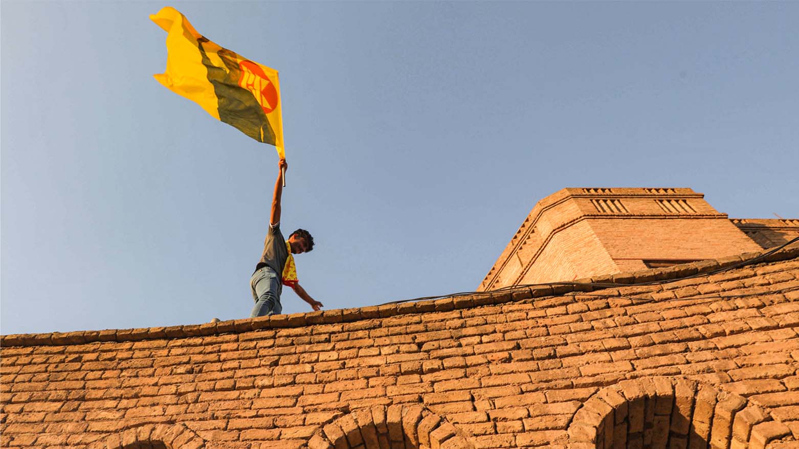 A KDP supporter wave his party's flag at ancient Erbil citadel in Kurdistan Region's capital during an election rally, Oct. 7, 2021. (Photo: Safin Hamed/AFP)