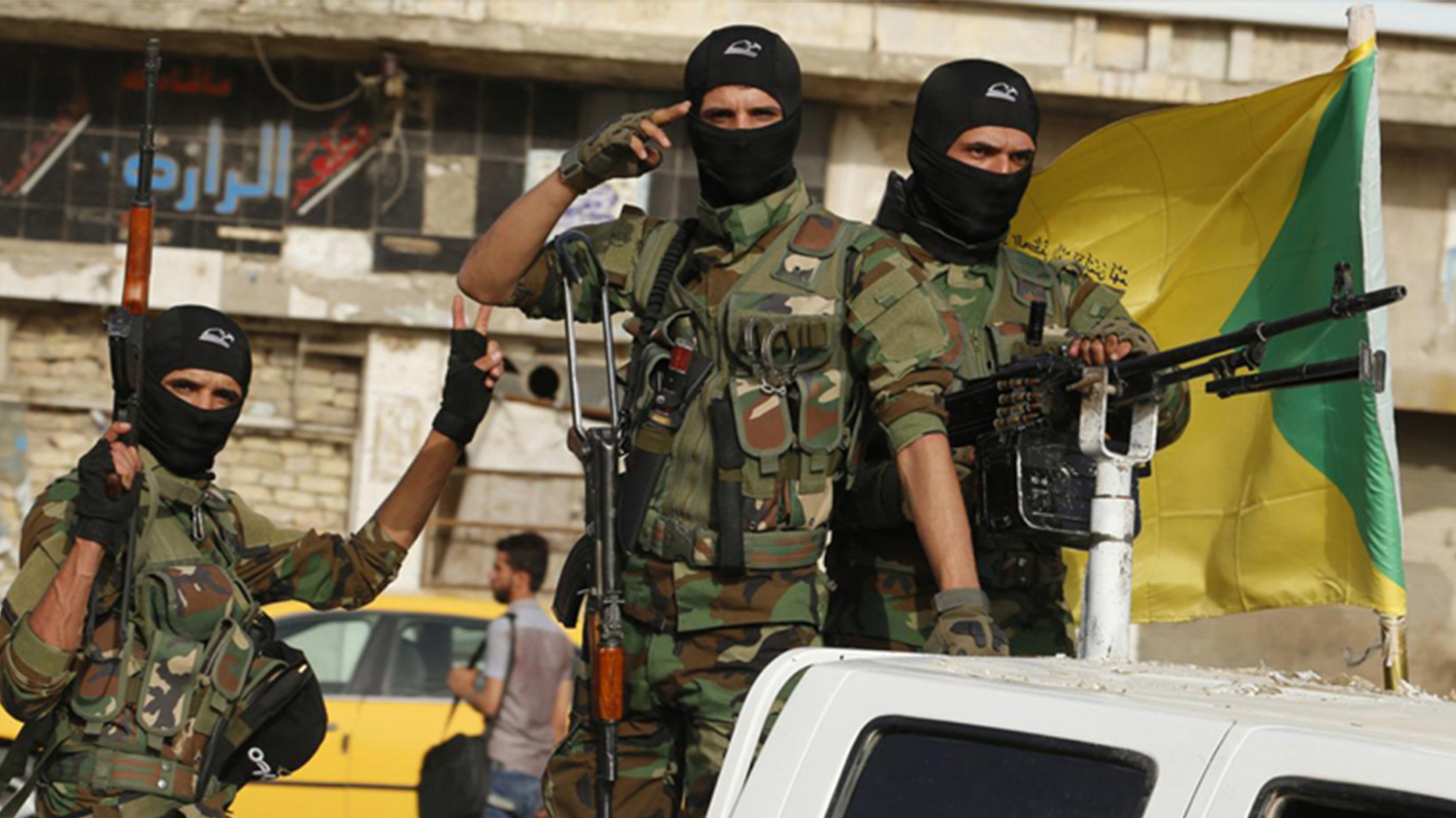 Masked members of Iraq's Shia militia, Kata'ib Hezbollah, holding their weapons as their convoy arrived in Baghdad's Karada neighborhood (Photo: AFP)