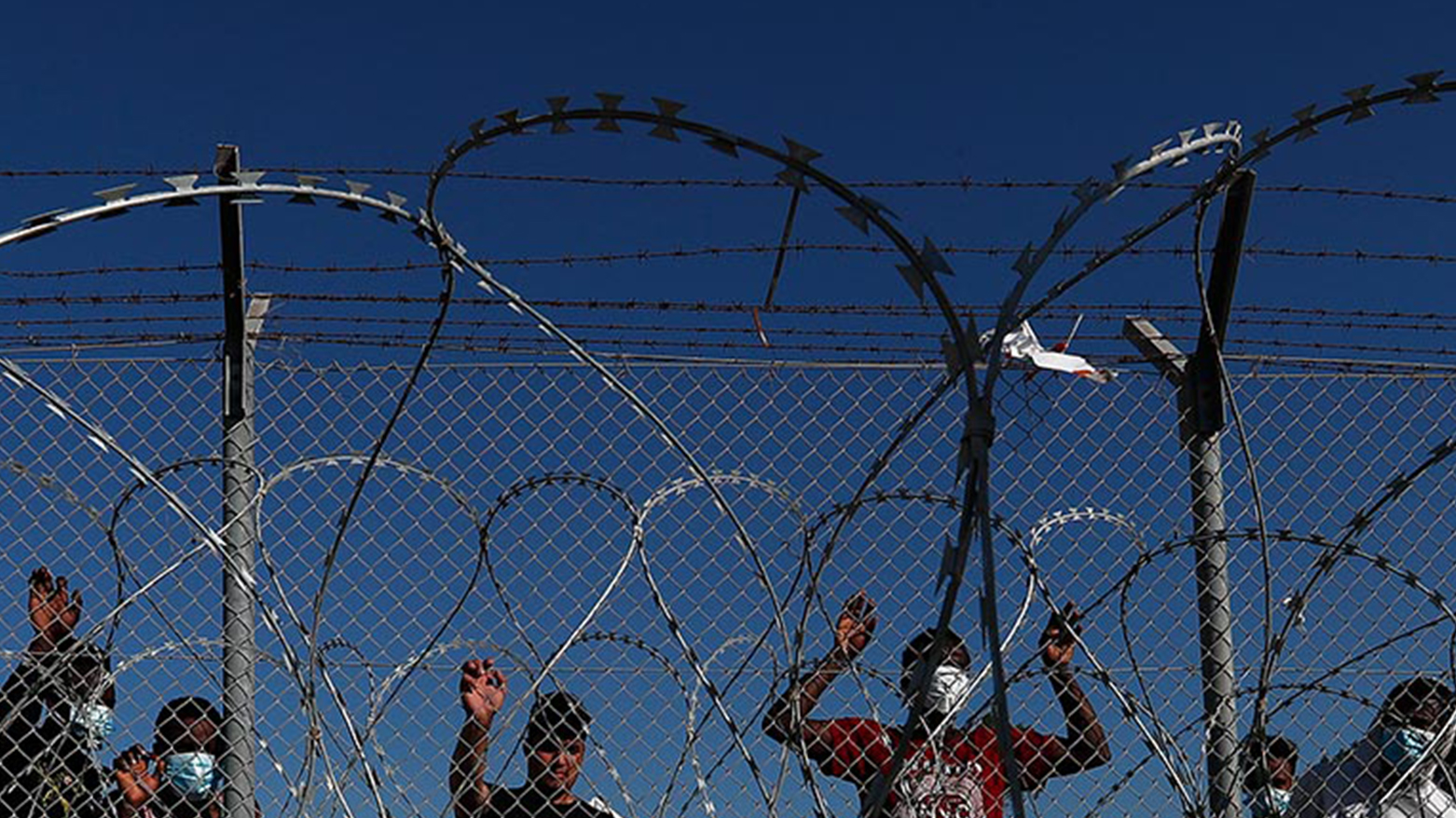 Migrants stand behind a fence inside a refugee camp in Kokkinotrimithia outside of capital Nicosia, Cyprus, Feb. 5, 2021. (Photo: Petros Karadjias/ AP)