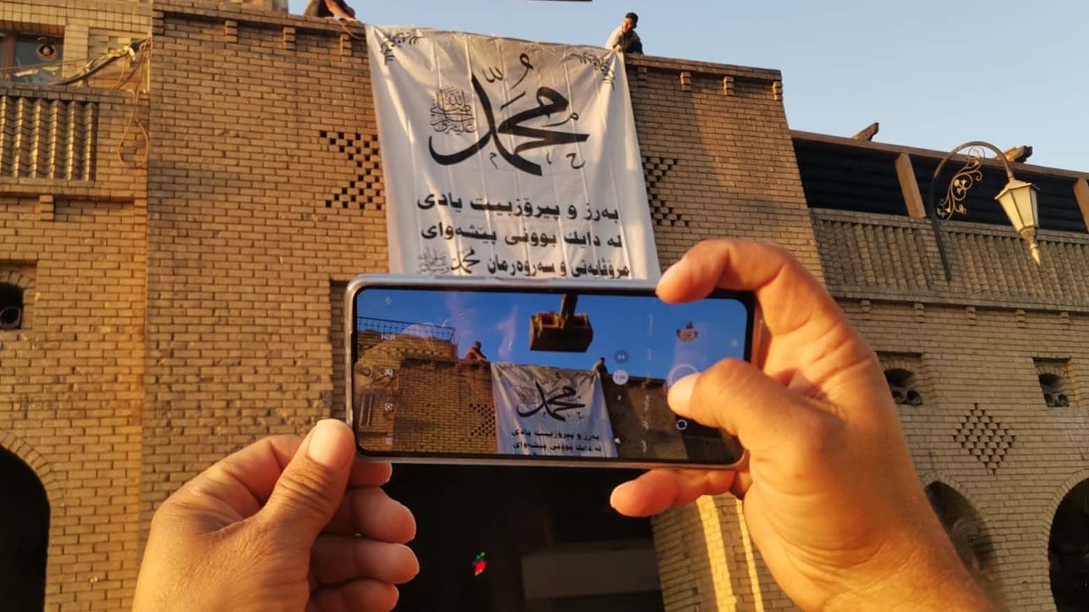 A man takes a photo of a wall poster celebrating Prophet Mohammed's birthday in Erbil, Sept. 20, 2023. (Photo: Erbil Governorate)
