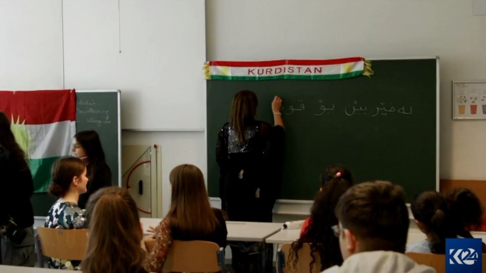 A teacher writes on a blackboard in the new Kurdish school in Vienna. (Photo: Kurdistan 24)