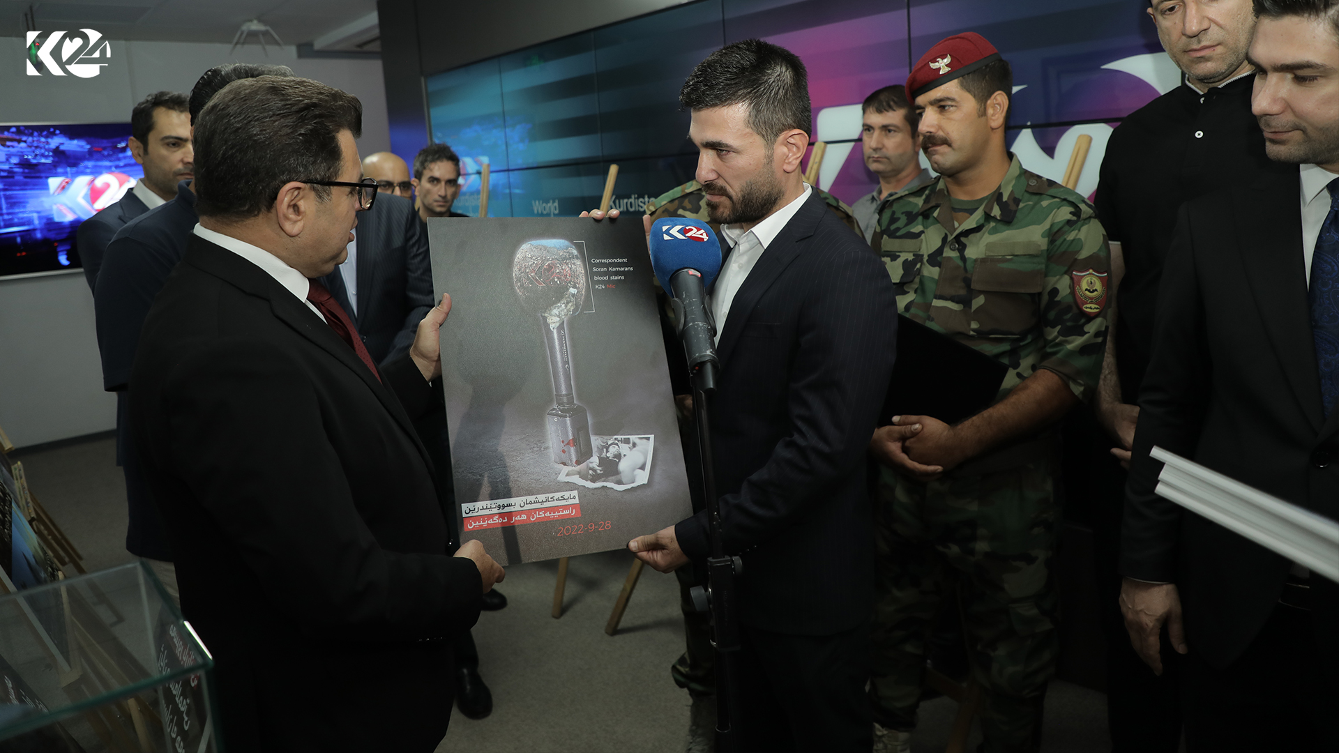 Kurdistan 24 Kirkuk reporter Soran Kamaran (right) presenting a photo of the Kurdistan 24 blood-stained mic to General Manager Ahmed Al-Zawiti, Sept. 28, 2023. (Photo: Kurdistan 24)