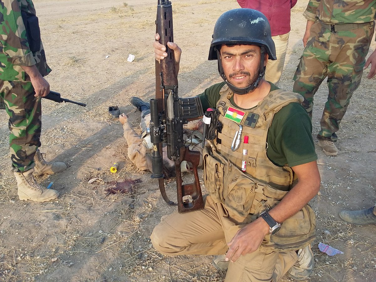 A Peshmerga bolunteer stands close to a dead IS extremist